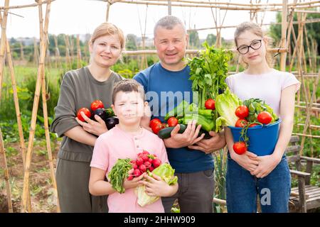 Happy family with fresh harvest in backyard garden Stock Photo