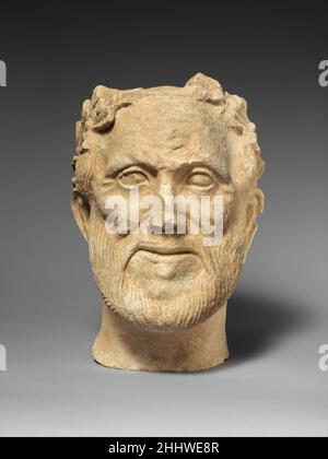 Limestone head of bearded male votary with wreath of leaves 1st century B.C. Cypriot The face, with a short beard and a drooping, delicately combed mustache, is that of an elderly man. The deep lines on the cheekbones, the forehead, and around the deep-set eyes surmounted by thick eyelids confirm his age.. Limestone head of bearded male votary with wreath of leaves  242362 Stock Photo
