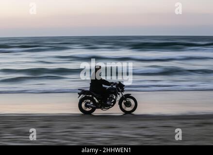 Gaza, Palestine. 25th Jan, 2022. A Palestinian rides a motorbike during sunset on the seashore west of Gaza City. Credit: SOPA Images Limited/Alamy Live News Stock Photo