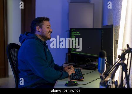 Happy bearded Caucasian programmer happily typing on his computer keyboard and enjoying the process Stock Photo