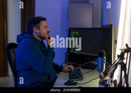 Bearded Caucasian programmer typing on his computer keyboard and thinking how to solve the issue Stock Photo