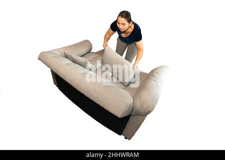 An Asian female maid is putting pillows and cleaning the sofa in the room. Stock Photo