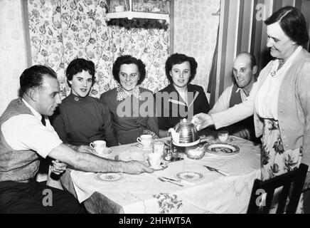 Liverpool full back Ronnie Moran  has a cup of tea poured for him bis mother at home. Waiting their turn are his girfriend Joyce, his sisters Dixie and Peggy and brother Tom. 26th October 1955. Stock Photo