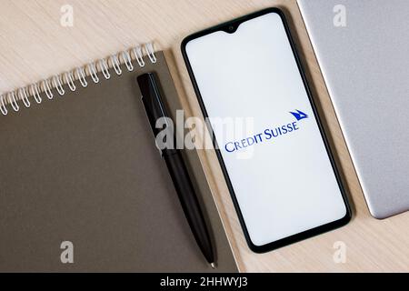 Smartphone with Credit Suisse bank logo on wooden table next to laptop and business planner Stock Photo