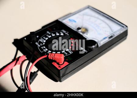 Analog multimeter measuring equipment for checking the amperage voltage at circuit breakers and wiring systems on main power distribution boards. Stock Photo