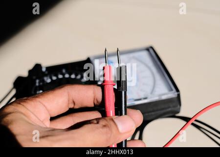 Analog multimeter measuring equipment for checking the amperage voltage at circuit breakers and wiring systems on main power distribution boards. Stock Photo