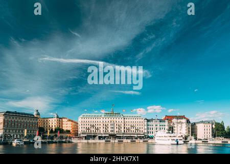 Stockholm, Sweden. Grand Hotel Located On The Peninsula Blasieholmen. Touristic Pleasure Boats Floating Near Famous Grand Hotel In Sunny Summer Day. Stock Photo