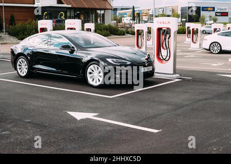 Black Color Tesla Model S 100d Car Parked At Charging Station. The Tesla Model S Is A Full-sized All-electric Five-door, Luxury Liftback, Produced By Stock Photo