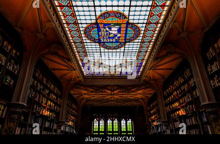 Porto, Portugal - May 30, 2018: Livraria Lello and Irmao bookshop shelves and stained glass ceiling. Inscription says Decus in labore or Honor in Work Stock Photo