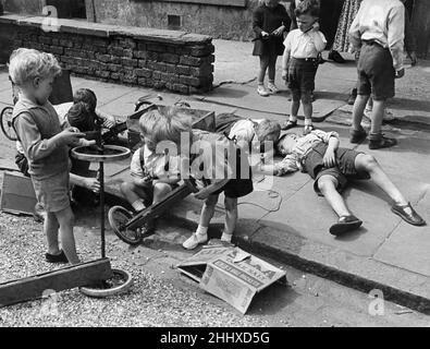 London children prepare for 'Soap Box Derby' June 1950.  A number of soap box Derby races are being arranged for London and provincial towns by several organizations.   Many scouts will take part and an artist at Boreham Wood is helping boys who will test their trollies on a course he has selected.   These small kiddies of Finsbury Park are going to have their own Derby. As soap boxes are in short supply they are getting material and old pram wheels form direlect sites to build their boxes on wheels. Stock Photo