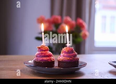 Berlin, Germany. 12th Jan, 2022. ILLUSTRATION - Two cupcakes with burning candles are placed on a table. (posed scene) Credit: Annette Riedl/dpa/Alamy Live News Stock Photo