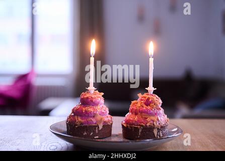 Berlin, Germany. 12th Jan, 2022. ILLUSTRATION - Two cupcakes with burning candles are placed on a table. (posed scene) Credit: Annette Riedl/dpa/Alamy Live News Stock Photo