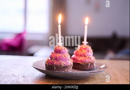 Berlin, Germany. 12th Jan, 2022. ILLUSTRATION - Two cupcakes with burning candles are placed on a table. (posed scene) Credit: Annette Riedl/dpa/Alamy Live News Stock Photo