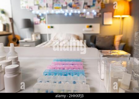 Part of hospital room with medicaments in plastic bottles, jars and containers on cart in front of camera Stock Photo