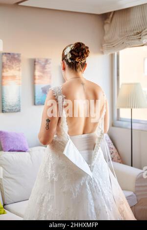 A female helps a bride get ready for the wedding Stock Photo