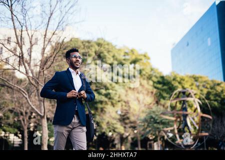Enterprising black man buttoning his jacket while walking down the street Stock Photo