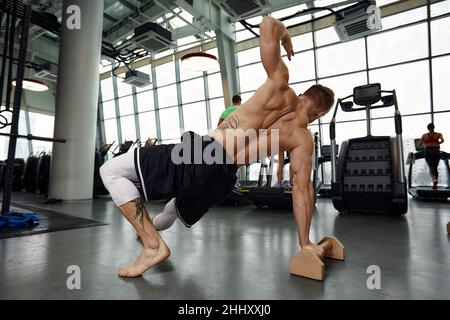 Healthy fitness man doing stretching in the gym using wooden sports equipment. Sport concept, fat burning and a healthy lifestyle Stock Photo