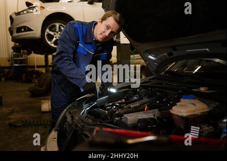 Technician automotive checking car in the garage. Auto mechanic working with engine in garage, car service technician repairing customer care at autom Stock Photo