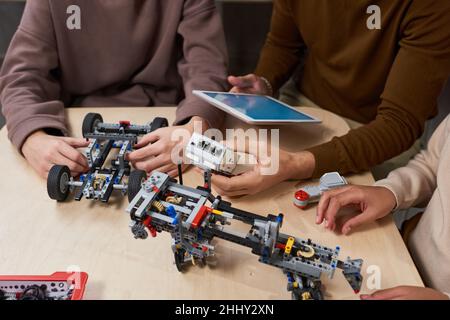 Close-up of students connecting robots with digital tablet at the table during engineering lesson Stock Photo