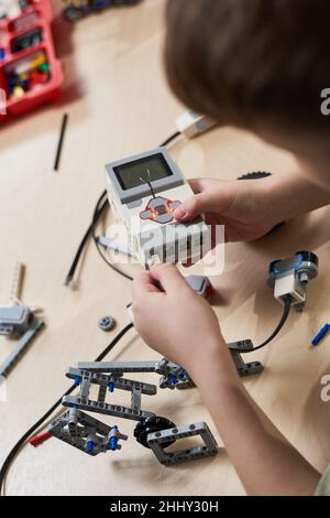 Close-up of boy building robot constructor from the plastics details programming on the computer at robotics school lesson Stock Photo