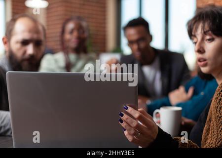 Multiracial businesspeople looking at laptop screen analyzing company turnover working at marketing strategy during business meeting in startup office. Multiethnic team brainstorming ideas Stock Photo