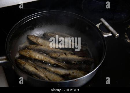 Fried herring on a frying pan. Stock Photo
