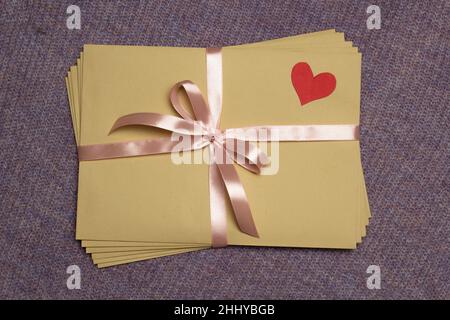 A stack of love envelopes with a heart tied with a ribbon. Stock Photo