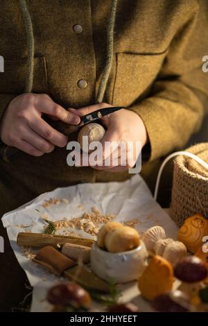 Carpenter carving wood with cutter knife. Female craftswoman creating wooden toys in workshop studio Stock Photo