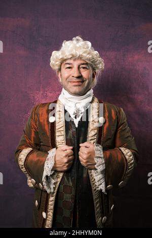 Man in classic medieval clothing smiling while posing holding his suit with his hands. Stock Photo