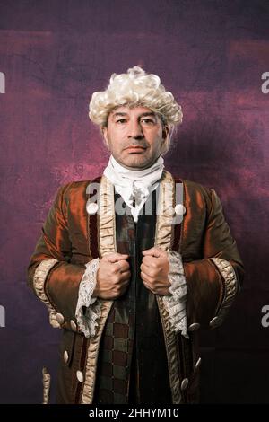 Serious man in classic renaissance clothes holding his suit while posing on isolated background. Stock Photo