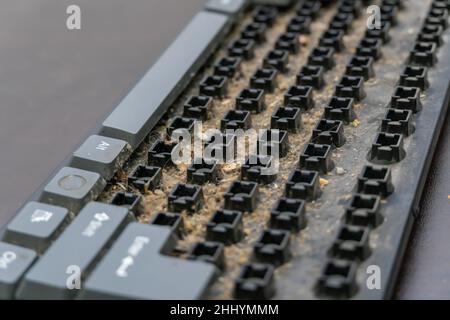Close-up of a very dirty disassembled computer keyboard on the table. Disassembling a computer keyboard with your own hands, cleaning the keyboard Stock Photo