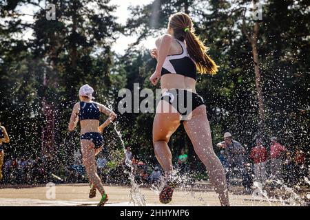 young female athlete run steeplechase in splashing water Stock Photo