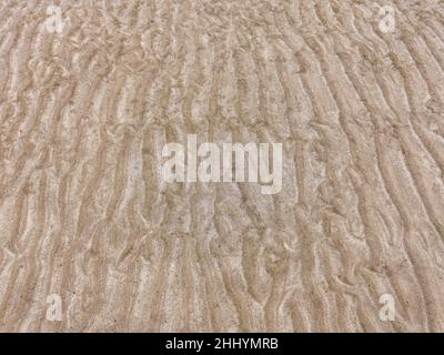 Sand on the beach for background. Brown beach sand texture as background. Close-up sand pattern. Top view wavy sand background for summer designs Stock Photo