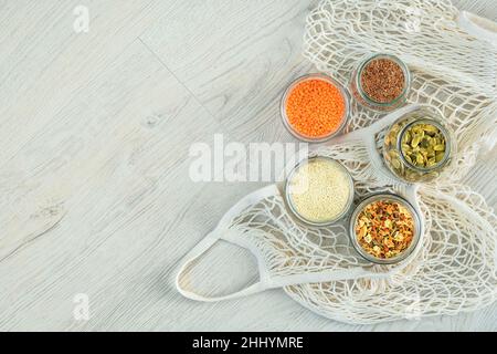 Flax and pumpkin seeds, sesame seeds, lentils and dry vegetables in glass jars on wooden background. Organic foods in zero waste store. Copy space. To Stock Photo