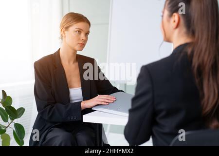 Job interview. Business, career and placement concept. Young blonde woman holding resume, while sitting in front of candidate during corporate meeting Stock Photo