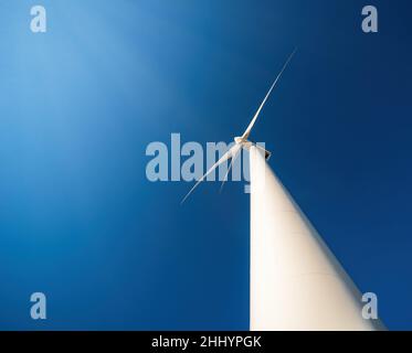 Wind generator against blue sky. Minimalistic shot, low point of view, dramatic perspective Stock Photo