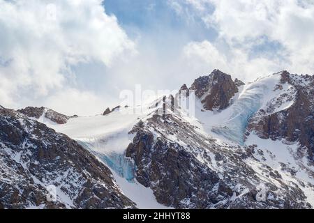Rocky mountain covered with ice and snow. Snow-capped peaks, winter mountains. Rocks and white slopes covered with glaciers. Stock Photo