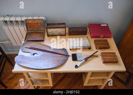 The work desk with paintbrushes, palette, paints and other things in his studio. At the painter Ural Tansykbayev house museum in Tashkent, Uzbekistan. Stock Photo