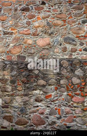 Wall of an old building made of untreated cobblestones and fragments of brick Stock Photo