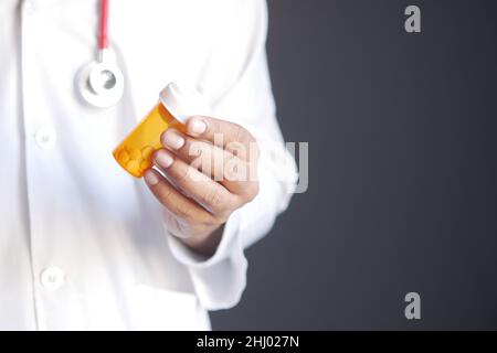 doctor holding pill container on black background  Stock Photo