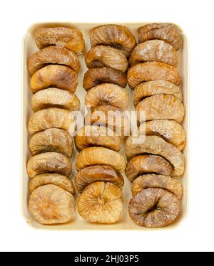 Sun dried figs, in a wooden tray. Three rows of dried, ripe and whole common figs, uncooked fruits of Ficus carica, a popular snack in wintertime. Stock Photo