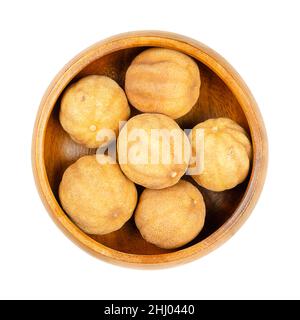 Whole, dried limes, noomi basra, in a wooden bowl. Small, brown, sun dried limes, also known as limoo amani or loomi. Used as flavor or herbal tea. Stock Photo