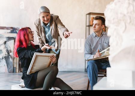 Mature teacher talking with her students during class in art school indoors Stock Photo