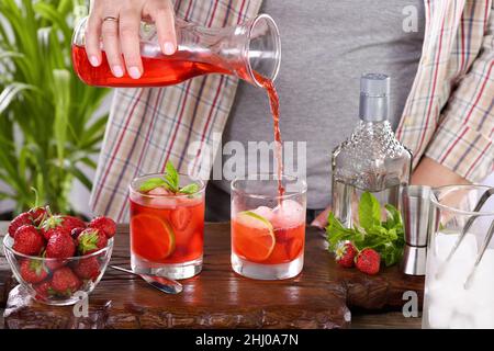 The bartender prepares a refreshing strawberry mojito cocktail with ice, fresh mint and lime. Great idea for a picnic or summer party. It may contain Stock Photo