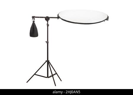 Round silver fabric reflector on stand with counterweight bag. Photography studio equipment isolated on white background. Stock Photo