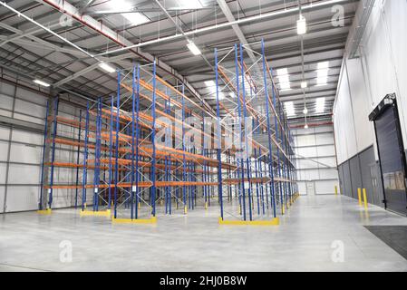 Empty shelves in a new warehouse. Racks in a distribution stockhouse. Concept suggesting supply shortages, logisitcal problems or stock issues. Stock Photo