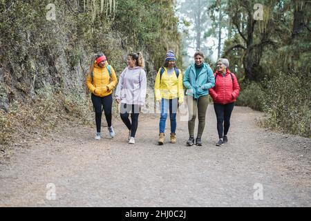 Multiracial women having fun during trekking day in mountain forest - Focus on faces Stock Photo