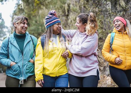 Multiracial women having fun during trekking day in mountain forest - Focus on faces Stock Photo