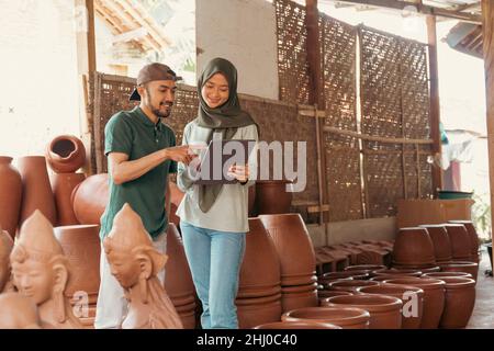 Man and woman in veil using tablet at pottery stall Stock Photo