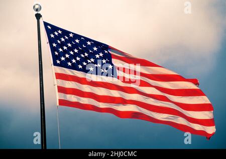 American Flag USA, United States of America stars and stripes on a flagpole fluttering in the wind. Oversized US American flag flying on a windy day. Stock Photo